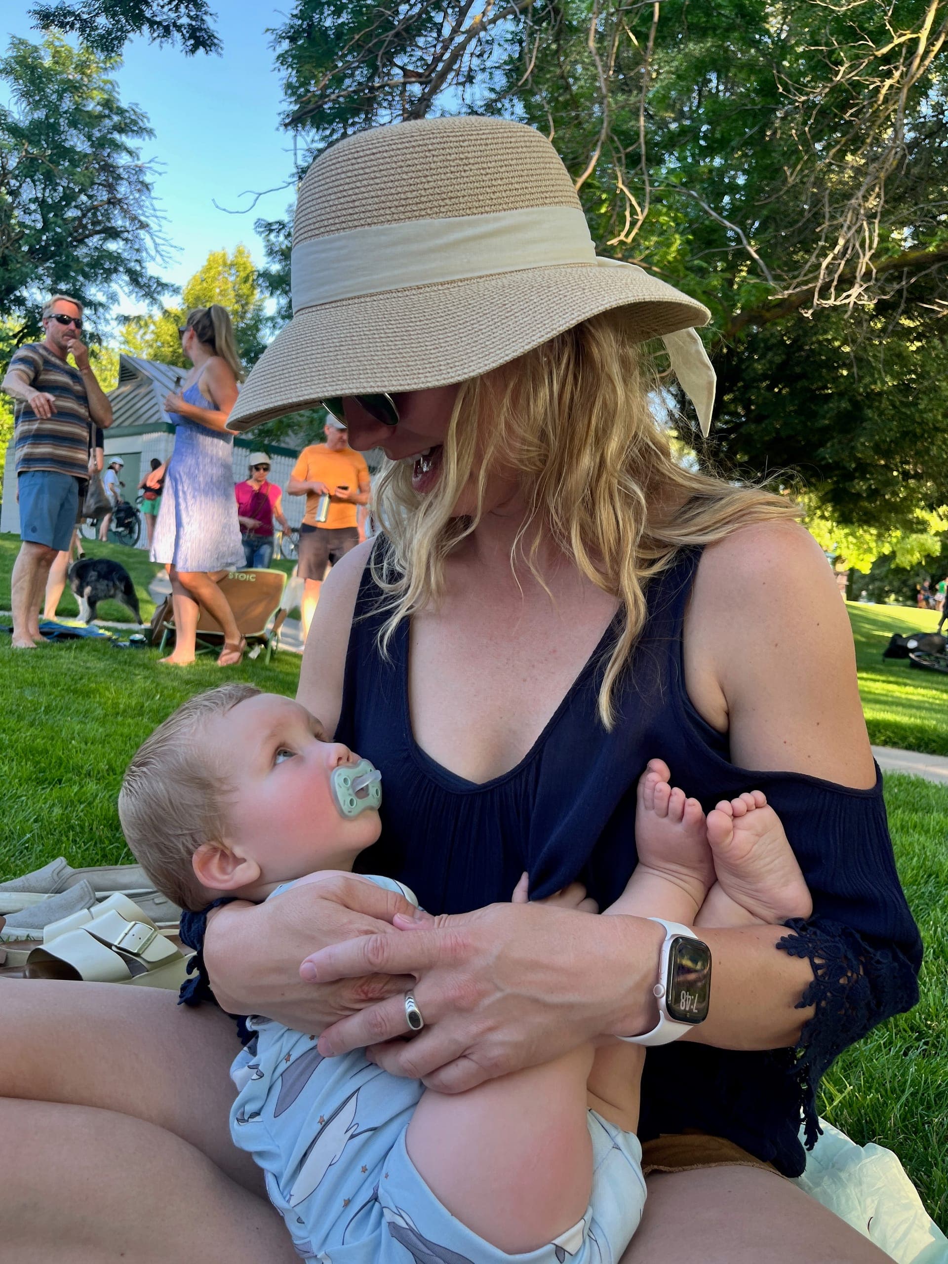 Sarah holding baby Ziggy sitting on a blanket in the park.