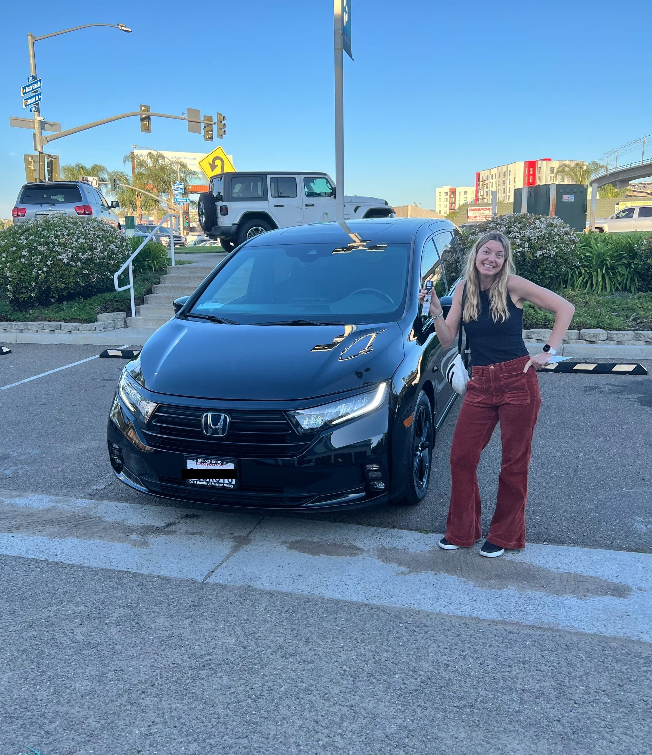 Sarah holding the keys to a newly purchased black Honda Odyssey.