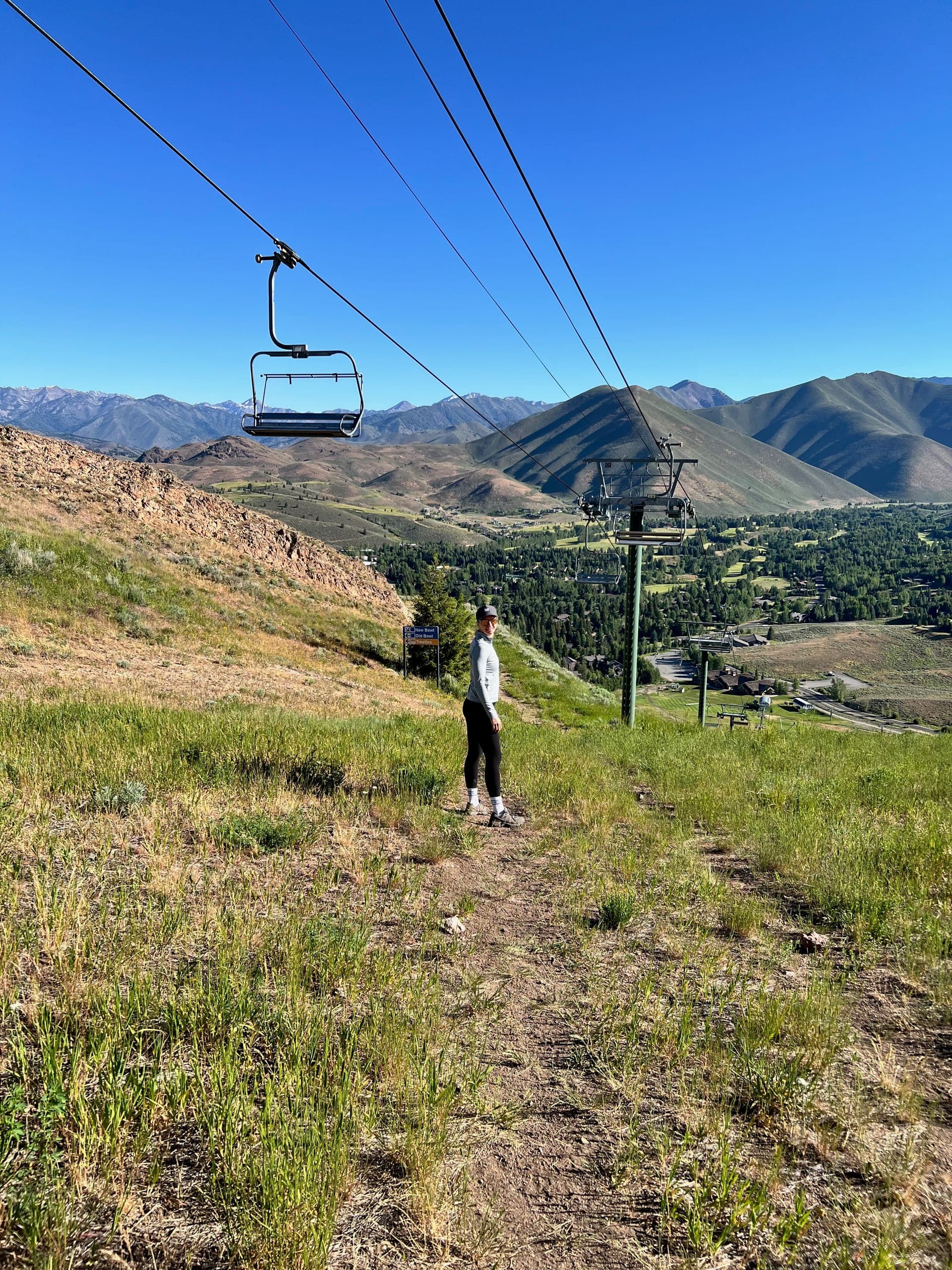 Sarah under the Dollar Mountain chairlift with a sign pointing to different runs in the background.