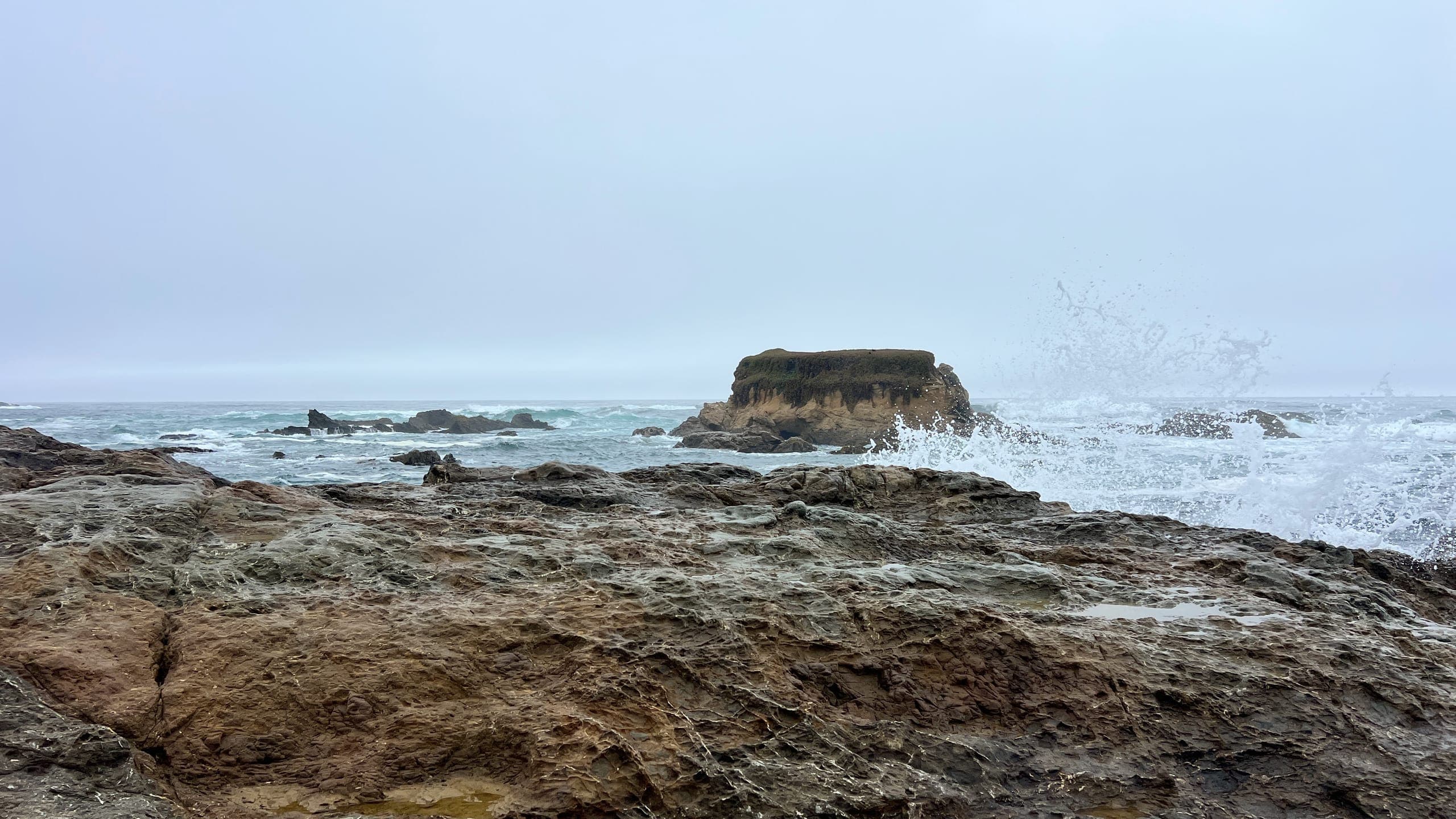 Sea spray cresting a rocky outcropping on the shore of Fort Bragg's Glass Beach.