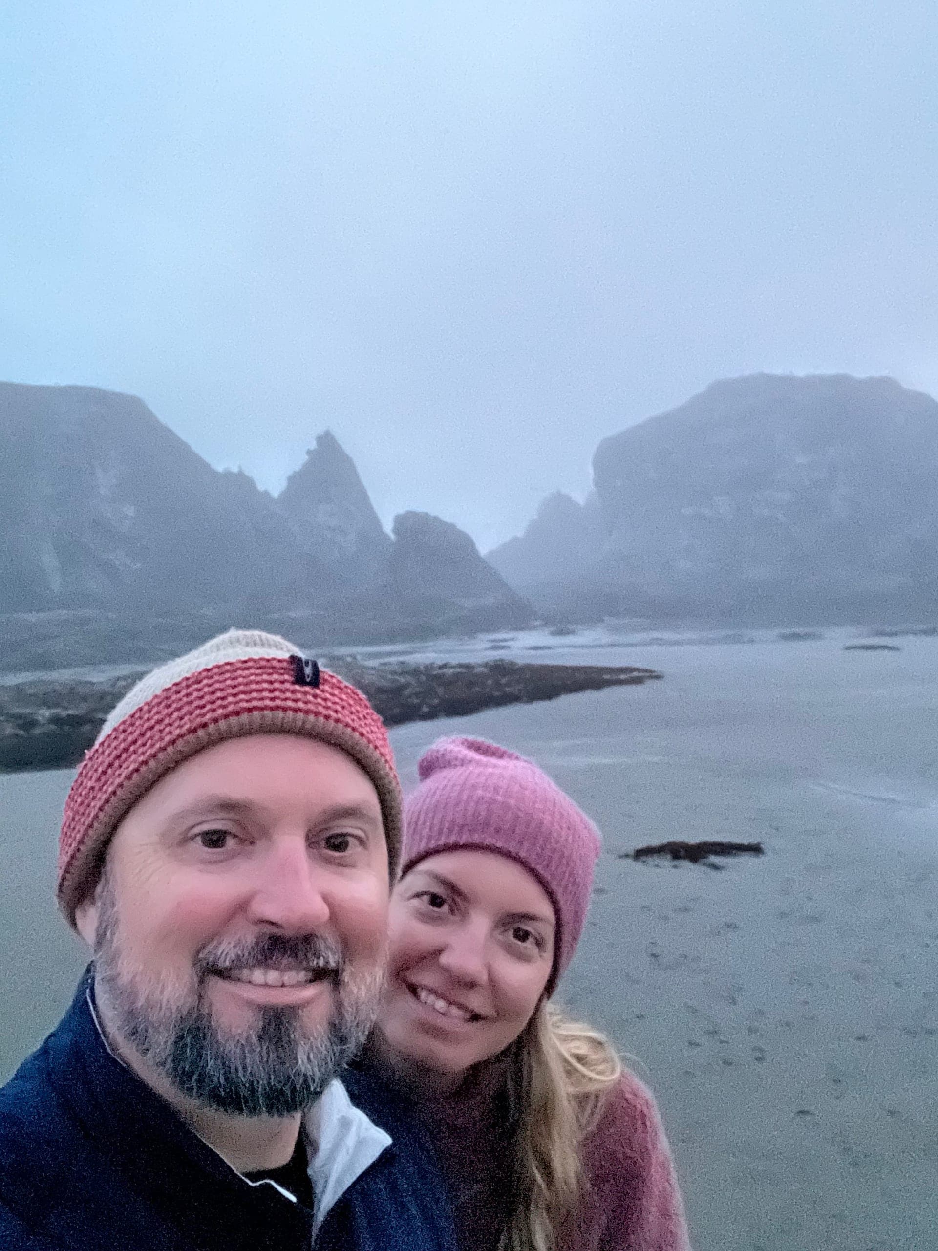 Selfie of Sarah and Erik standing on the sand at low tide on a foggy evening.