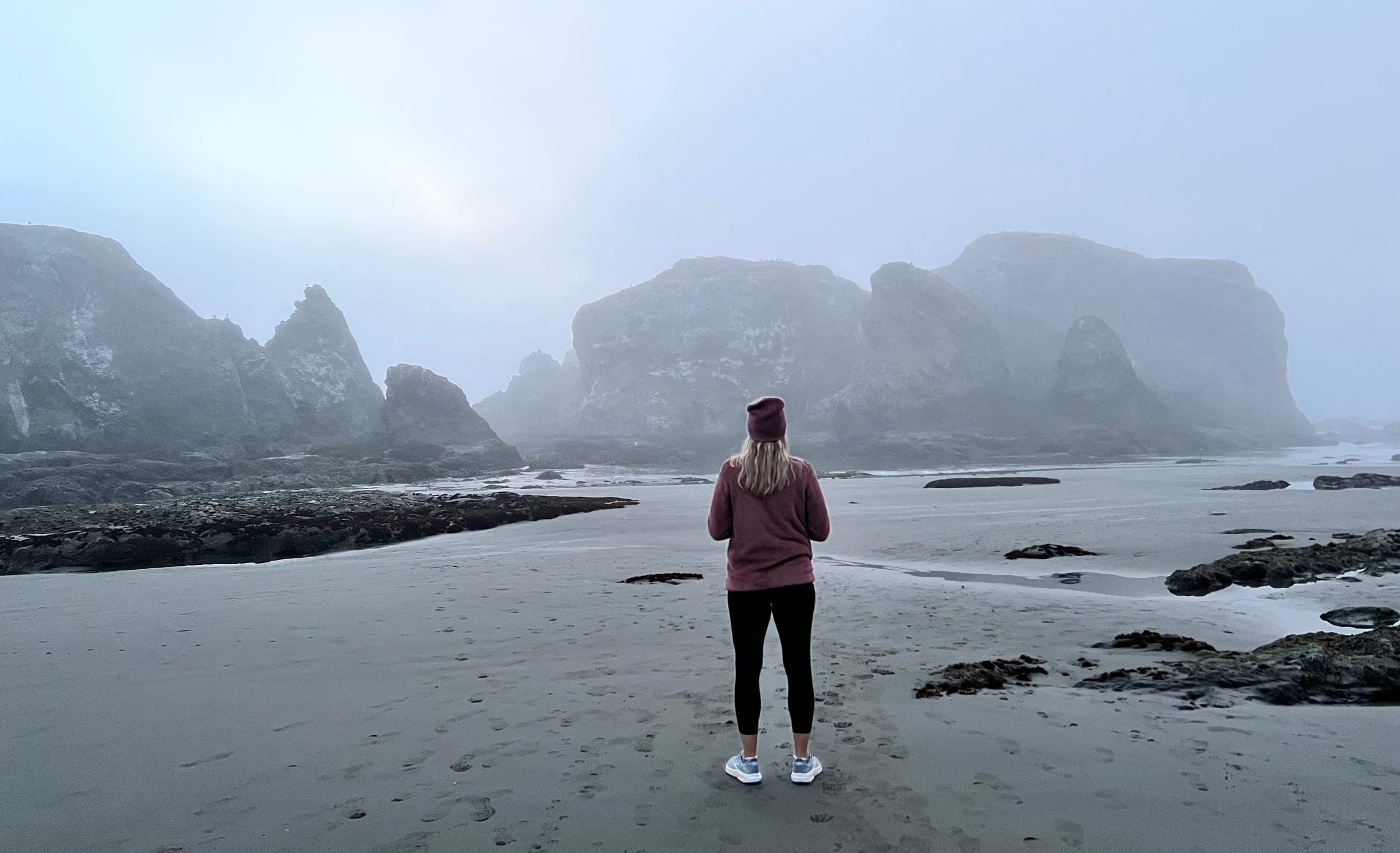 Sarah looking out to the coast line at low tide on a foggy evening.