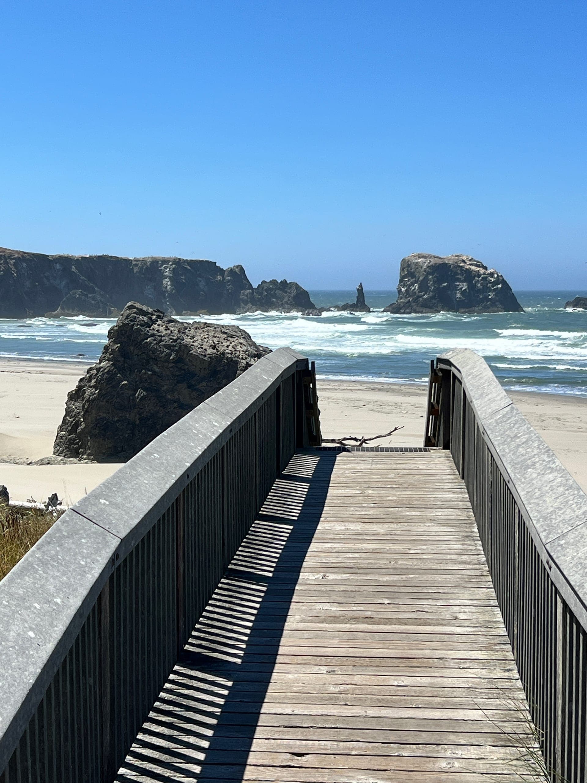 Pointy rock formations in the ocean viewed from a wooden walking bridge.